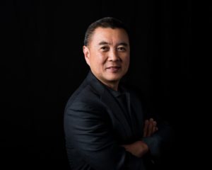 Headshot of an Asian man in Seattle office with black background