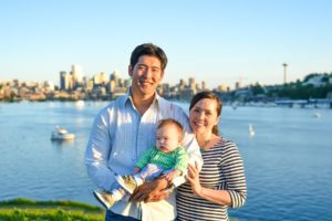 Mother and father holding their son at Gasworks Park with Seattle cityscape in the background