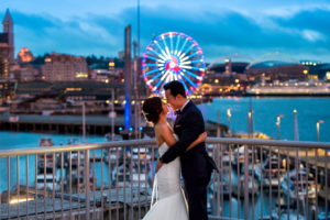 Bride and groom looking at each other on top of Bell Harbor Conference Center overlooking Seattle waterfront during sunset