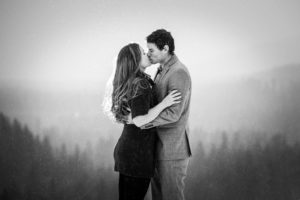 Black and white photo of couple kissing while snowing at Suncadia