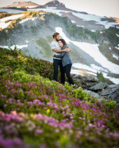 Couple embraces one another next to wildflowers at Mt. Rainier
