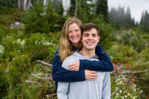 Couple facing camera with woman's arms wrapped around fiance at Mt. Rainier