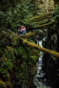 Couple hugging sitting down in forest with stream
