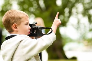 Boy with hooded sweatshirt directing people with camera
