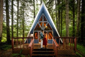 Couple looking at each other in front of mountain cabin near mt. rainier