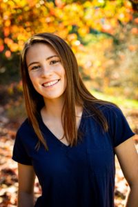 Girl smiling during her senior photos at the Arboretum in Seattle with autumn trees in the background