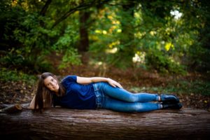 High school senior laying on a log for her senior photos