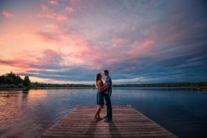 Couple looking at each other on dock at lake during sunset