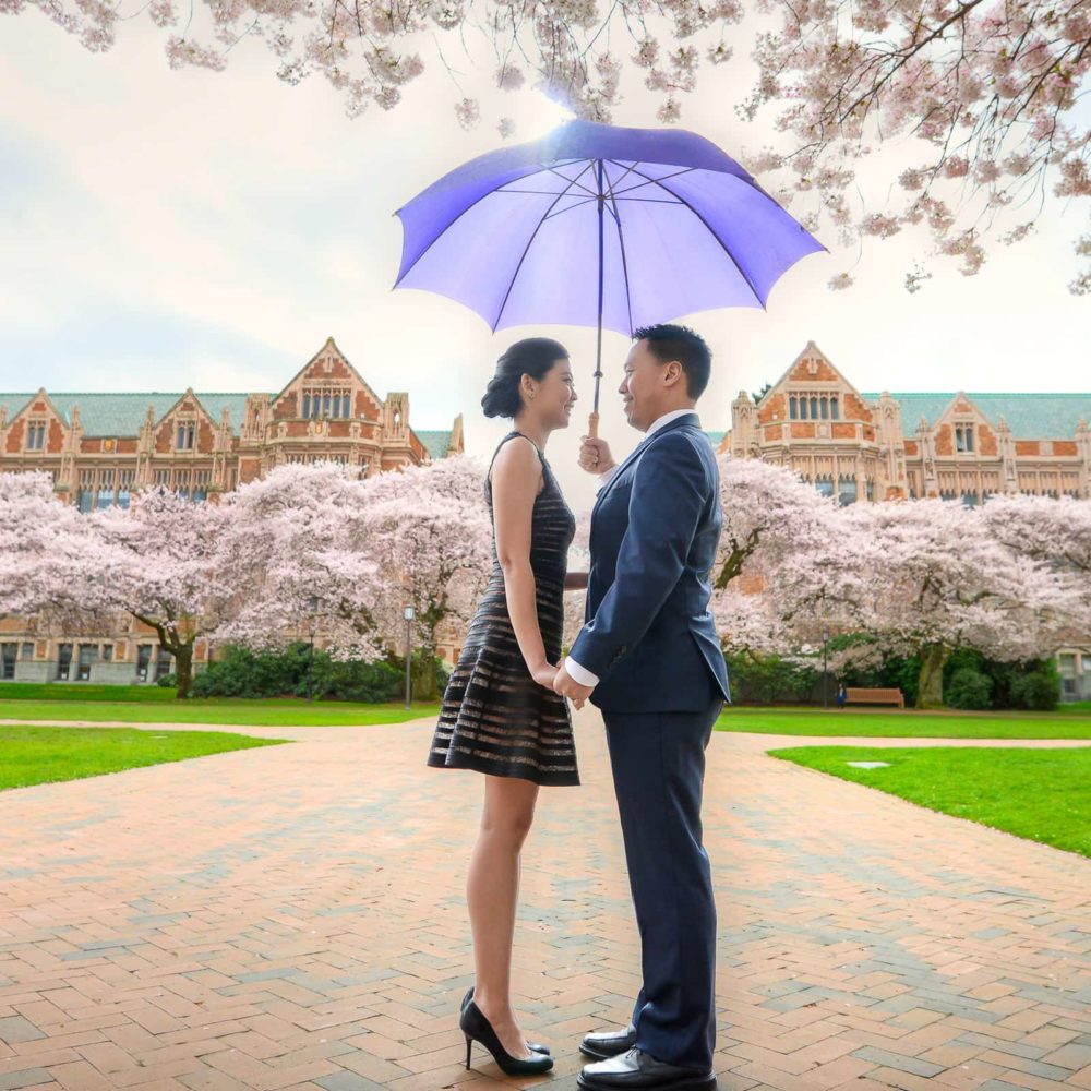 Couple at University of Washington holding umbrella while looking at each other
