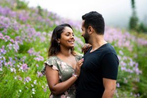 Couple looking at each other smiling in front of Mt Rainier wildflowers