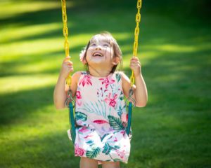 Girl on swing looking at sky and laughing