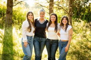 Mother wearing navy blue with three daughters wearing white shirts shirt and daughters