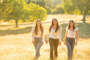 Three sisters wearing white shirts walking in field