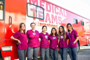 SPU nursing students smiling in front of Medical Teams International Vehicle