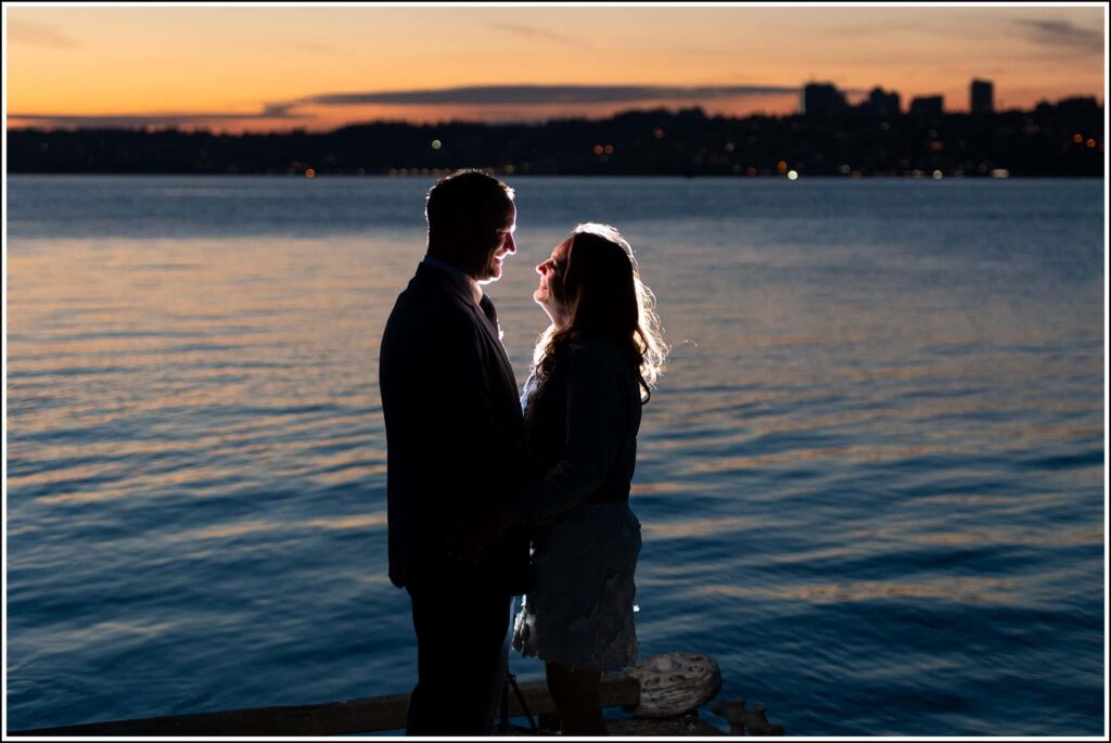 Newlyweds facing each other at sunset on a dock at Semiahmoo Resort overlooking Vancouver, BC
