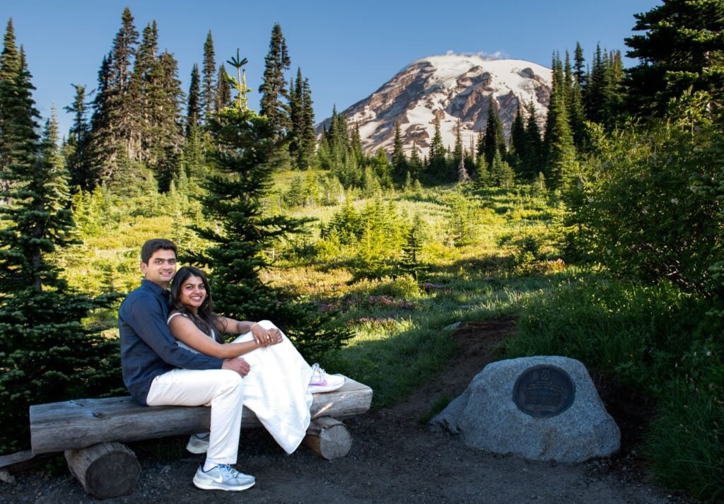 Couple sitting on bench facing camera with mt rainier in the background