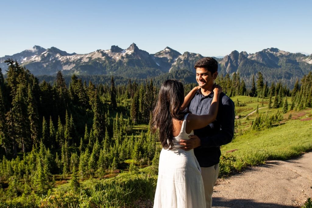 Couple newly engaged facing each other on mt. rainier with tatoosh range behind them