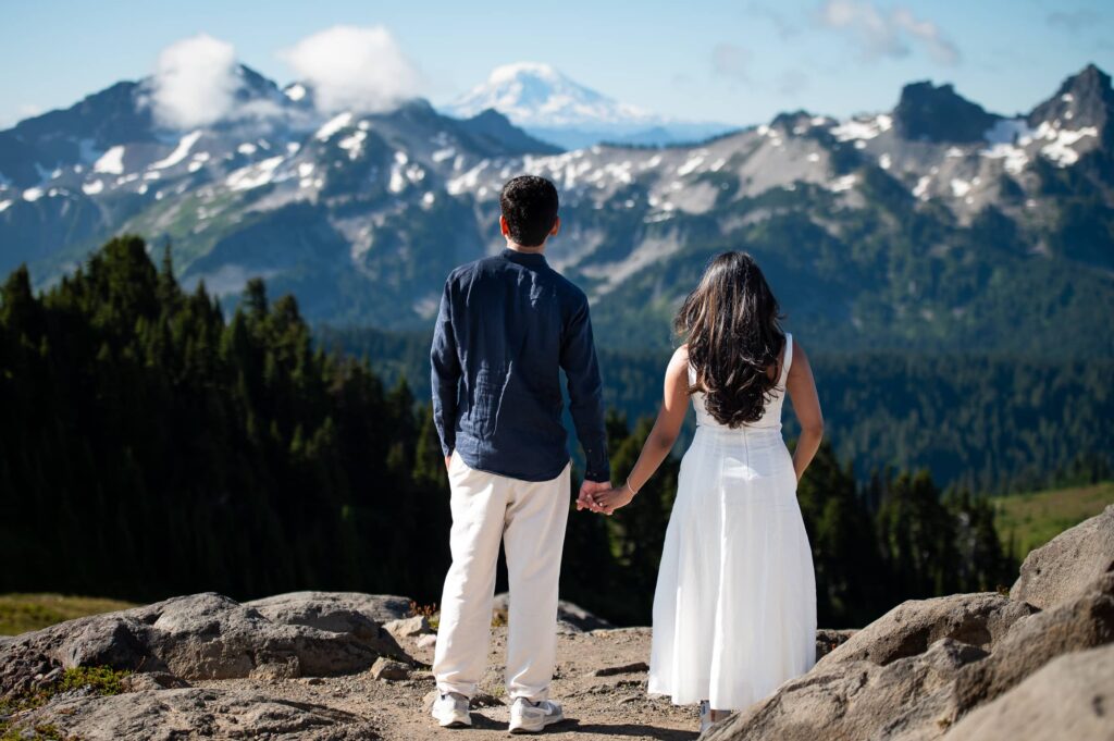 Nicely dressed couple holding hands facing away towards mt. adams