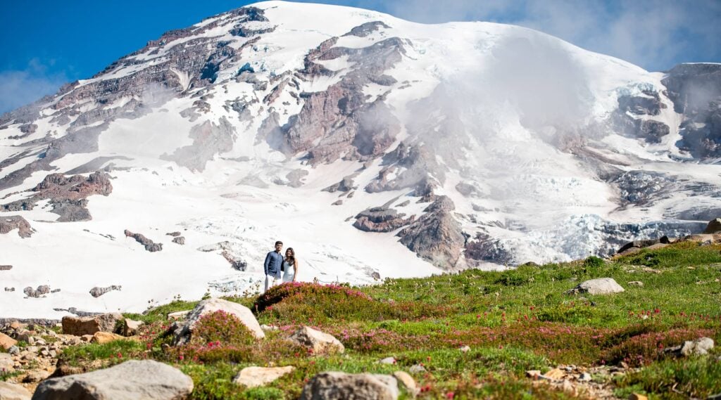 Mount Rainier with couple looking towards wildflowers and mountain behind them