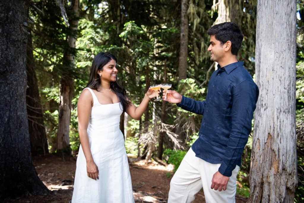 Couple toasting each other with sparkling beverage after he proposed to her at mount rainier
